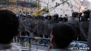 Egyptian protesters stand near barbed wire after being stopped by police February 2, 2012 in Cairo, Egypt