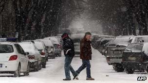 Two men cross a snowy street in Nis, Serbia on 2 February, 2012