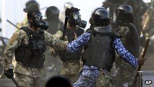 A Maldives police officer, in blue, charges soldiers during a clash in Male, Maldives, Tuesday, Feb. 7, 2012