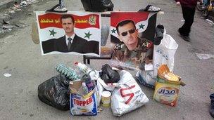 Pictures of Syria's President Bashar al-Assad are placed in the middle of a street among trash in Bab Sabaa neighbourhood of Homs