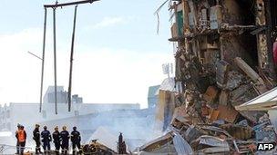 Rescuers stand at the smoking ruins of the CTV building in Christchurch, New Zealand on 24 February, 2011