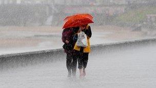 People share an umbrella on Whitley Bay, Yorkshire, during the wettest August in Britain on record, 2008