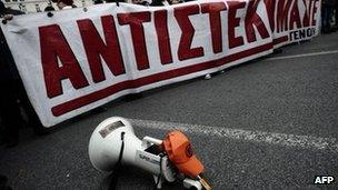 A megaphone lies in the road in Athens beside protesters with a banner reading "We resist", 9 February