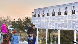 Residents look at a presidential election poster depicting the candidates in Ashgabat, Turkmenistan