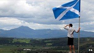 A man holds Scotland's flag aloft as he looks out over the Carse of Stirling