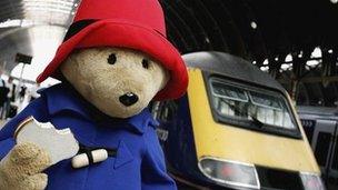 Paddington Bear with marmalade sandwich in hand, about to board a train at Paddington station