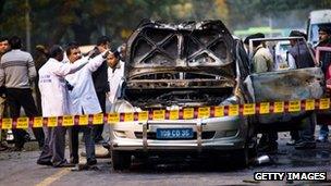 Police and forensic officers examine a bomb damaged Israeli embassy vehicle in Delhi, India