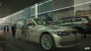 Pedestrians reflected in the window of a BMW car dealership in Beijing