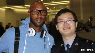 French soccer player Nicolas Anelka of Shanghai Shenhua poses with a Chinese immigration officer at Shanghai Pudong airport 15 February 2012