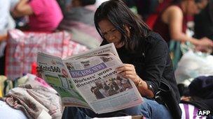 A domestic worker reading a newspaper