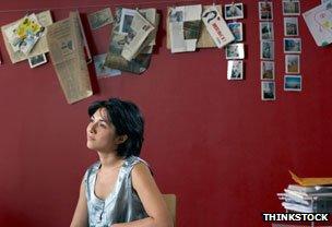 Woman in office, wall decorated with postcards and artworks and drawings