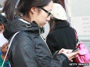 A woman sends a message on her smartphone