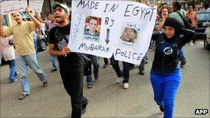 Protesters hold up a sign "Made in Egypt by Mubarak and Police" alongside shots of Khaled Said before and after his brutal death