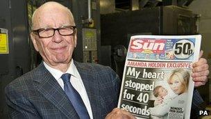 Rupert Murdoch holds the first edition of the Sun on Sunday newspaper