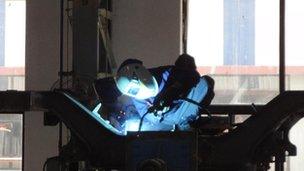 Worker welding railway bogie at Bombardier Transportation factory in Savli