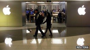 A couple walks past an Apple store in Shanghai