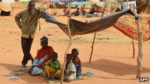 A woman and her children sit under a shelter at a Malian refugees camp in Chinegodar, western Niger (4 Feb 2012)