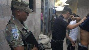 Soldier stands guard as police look for drugs and weapons in San Salvador, El Salvador's capital in January 2012