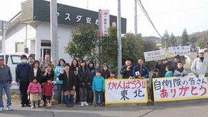 Residents hold thank you cards to Self Defence Force