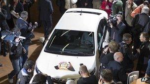 Cameramen and journalists crowd around a car at the motor show