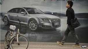 A pedestrian passes a billboard for a foreign car on a street in Shanghai