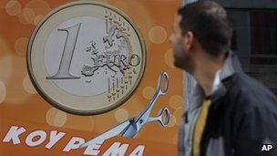 A pedestrian looks at a sign in a shop in Athens reading "One euro, price haircut"