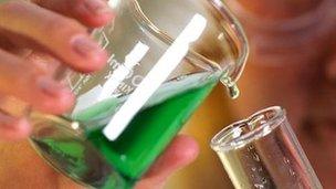 Laboratory technician pouring liquid from beaker into glass tube