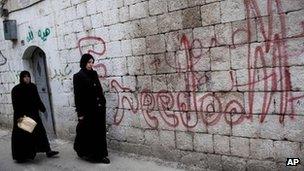 Women walk past graffiti saying "Freedom" in the Syrian city of Idlib (11 March 2012)