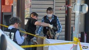 A French policeman holds a bloodstained jacket at the site of the shooting in Montauban, south-west France, 15 March