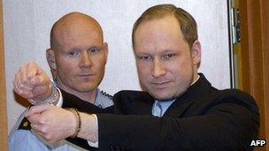 Anders Behring Breivik (right) with a police guard arrives in court in Oslo, 6 February