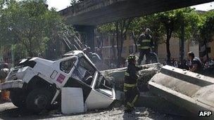 Firefighters work to remove a bus damaged by a bridge which collapsed following a strong earthquake that hit Mexico on 20 March 2012