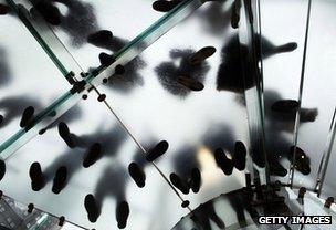 Customers' feet seen through the glass stairs at an Apple store