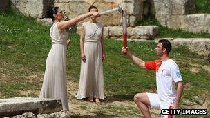 High Priestess Maria Nafpliotou lights the torch of first torchbearer Alexandros Nikolaidi in the Ancient Stadium during the Lighting Ceremony of the Olympic Flame at Ancient Olympia on 24 March 2008 in Olympia, Greece