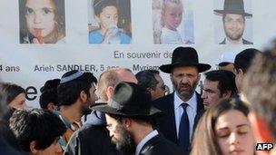 Jews gather beneath photos of the victims of the massacre at the Ozar Hatorah Jewish school in Toulouse, 25 March