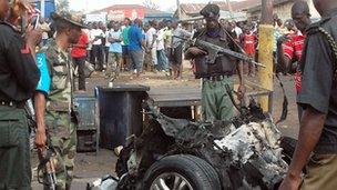 Security personnel inspect the mangled remains of a bomb-laden car that exploded in the northern Nigerian city of Kaduna on 8 April 2012