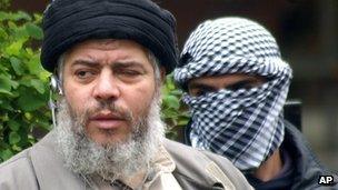 Abu Hamza (left) with a masked bodyguard