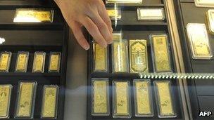 In a picture taken on March 2, 2011 a Chinese sales assistant arranges gold bars at a gold jewellery shop in Hefei, in east China's Anhui province.