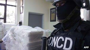 Dominican drug squad policeman stands guard next to packs containing cocaine, March 2012