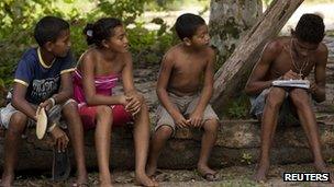 A boy does his homework as others watch in Sao Domingos do Capim March 10, 2012.