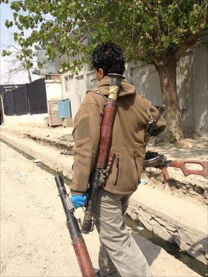 An Afghan soldier carrying weapons left behind by insurgents