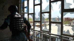 A member of the Afghan security forces searches a damaged Kabul building, 16 April