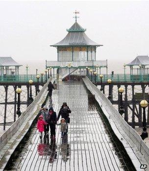 Holidaymakers walking on a pier in the rain (Image: AP)