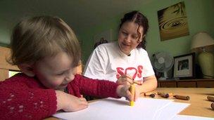 Toddler drawing with mum watching in the background