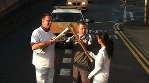 Volunteers touch torches to simulate passing the Olympic Flame