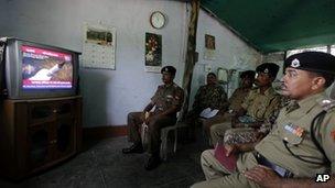 Indian Border Security Force officers watch television coverage of the launch of India's Agni-V missile