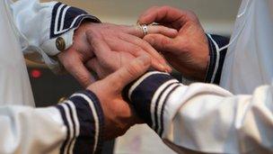 A man putting a wedding ring on another man's hand