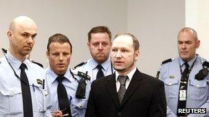 Police officers with Anders Behring Breivik in the Oslo court room where he is being tried