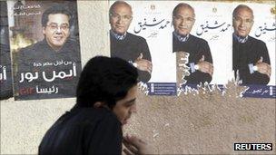 A young man walks past ripped campaign posters for Ahmed Shafiq in Cairo (right)