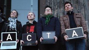 Protesters hold up laptops spelling out "Stop Acta"