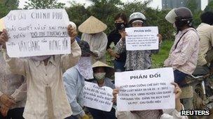 Farmers hold signs during a protest to protect their paddy fields from being part of a land grab to make way for the construction of a luxury Ecopark resort in Van Giang district, in Vietnam's northern Hung Yen province, outside Hanoi April 20, 2012